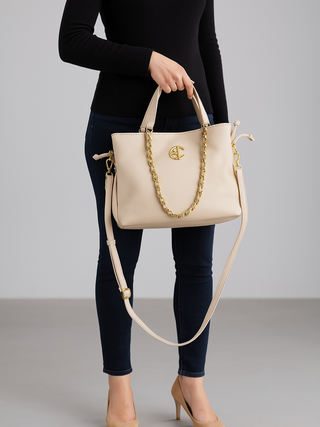 Enrico Coveri Shopper beige, eine elegante Handtasche in weichem Kunstleder mit goldenem Kettendetail und EC-Logo, wird von einer Person gehalten.