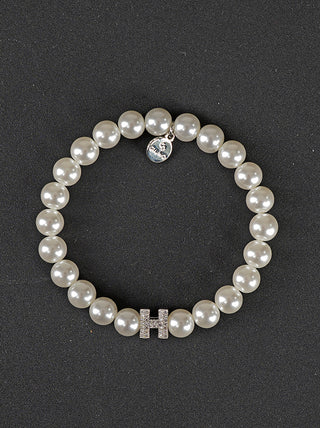 OFF#DLY Perlenarmband H Zirkon white: Ein Armband aus Kunstperlen mit einem silbernen Anhänger und einem Buchstaben, gefertigt aus hochglanzbeschichtetem Kupfer.