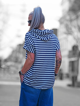 OFF#DLY Ringel m. Kapuze white/blue: Frau trägt gestreiftes Kurzarmshirt mit Kapuze und Tunnelzug, kombiniert mit blauen Jeans, ideal für lässige, maritime Looks.