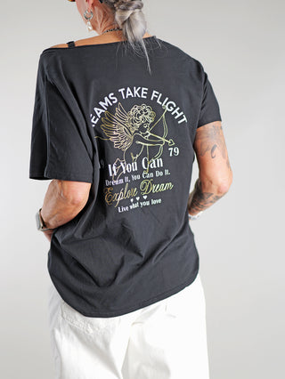 OFF#DLY Tee Angel blackgold mit goldfarbenem Print, getragen von einem Mann. Das T-Shirt zeigt den Schriftzug „Dreams take flight“ in Gold auf schwarzem Hintergrund.
