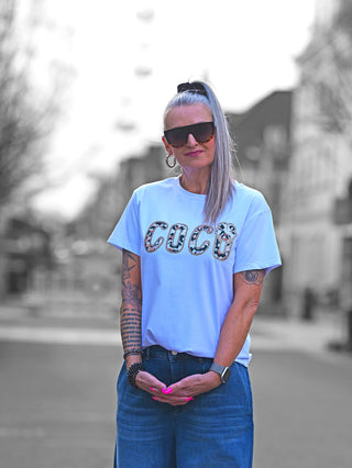 T-Shirt „COCO“ mit animalischem Frottee-Schriftzug und glitzernder Umrandung auf weißem Stoff, figurumspielend mit klassischem Rundhalsausschnitt. Ideal für einen femininen, lässigen Look.