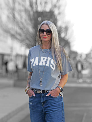 Frau trägt Off#DLY Tee paris grey mit PARIS Print, kombiniert mit Sonnenbrille und Jeans.