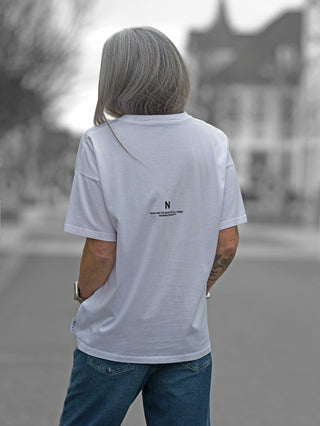 Nuomeno Oversized Tee Nube: Person trägt ein locker geschnittenes, weißes Baumwoll-T-Shirt mit schwarzem Rückendruck, zeigt den Rücken und einen Teil der Hose.