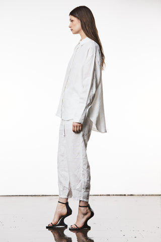 Thom Krom Bluse WH18 offwhite: Frau in lockerem, langärmligem Leinen-Baumwoll-Hemd mit langen Manschetten und abgerundetem Saum, kombiniert mit High Heels.