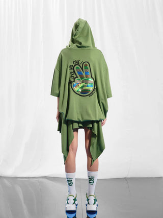 Eine Person trägt den #VDR Sweater oliv mit Kapuze und auffälligem Pailletten-Peace-Zeichen auf dem Rücken, kombiniert mit weißen und grünen Sneakers.