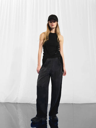 #VDR Top 17011 black: Frau trägt ein schwarzes, eng anliegendes, geripptes Tanktop mit Racerback-Schnitt, perfekt für lässige und sportliche Styles. Ideal unter Blazern oder solo.