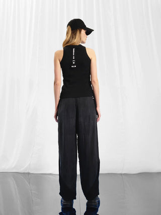 #VDR Top 17011 black: Frau trägt ein eng anliegendes, geripptes Tanktop mit Racerback-Design, ideal für sportliche und lässige Looks. Perfekt kombinierbar mit Hosen oder Röcken.