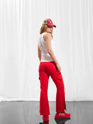 Frau trägt #VDR Top 17011 bianco, ein figurbetontes, geripptes Tanktop mit sportlichem Racerback-Design, kombiniert mit roten Hosen. Perfekt für lässige und cleane Alltagslooks.