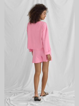 Frau trägt Cotton Candy Tee Nora offwhite, ein lässiges Langarmshirt mit Rundhalsausschnitt und Rückendetail, zeigt eine entspannte, übergroße Passform. Passend zu einem stilvollen, bequemen Look.