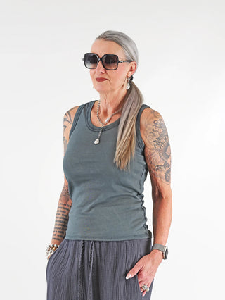 OFF#DLY Top Neve wash black: Frau trägt ein ärmelloses Baumwoll-Top mit Smiley-Patch, modisch kombiniert mit Sonnenbrille und Tattoos sichtbar; lässiger Rundhalsausschnitt, ideal für sommerliche Outfits.