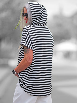 Ein gestreiftes Kurzarm-Shirt mit Kapuze, bekannt als OFF#DLY Ringel m. Kapuze white/black, zeigt eine lockere Passform und Tunnelzugkapuze, ideal für einen entspannten, maritimen Look.