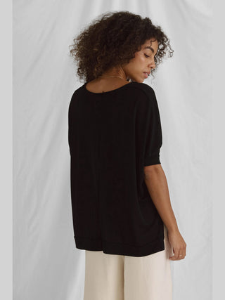 Frau trägt das Cotton Candy Tee Helay black, ein oversized schwarzes T-Shirt aus Viskose-Polyester-Mix mit V-Ausschnitt, sichtbar angenehm zu tragen. Model ist 1,76 m groß, trägt Größe S.