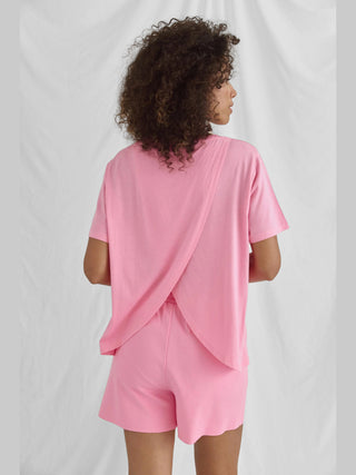 Cotton Candy Tee Azra pink, ein weiches, lässiges T-Shirt mit Rundhalsausschnitt und Rückenwrap, zeigt den Frontprint GOOD TIMES. Model trägt Größe S bei einer Größe von 1,76 m.