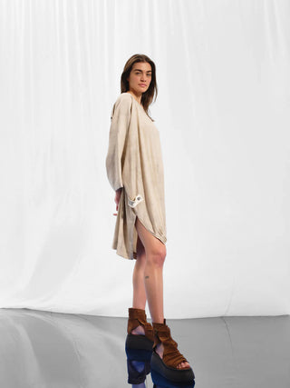 Frau trägt #VDR Tunica beige, eine oversized Tunika mit weitem Rundhalsausschnitt und halblangen Ärmeln, kombiniert mit braunen Keilsandalen.