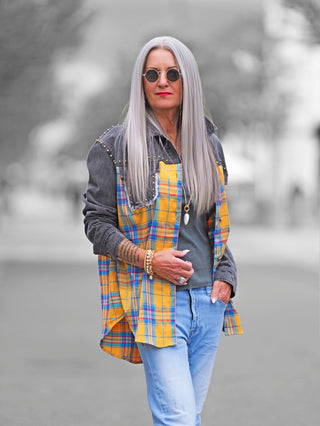 OFF#DLY Blusenjacke Denim: Frau trägt grau-gewaschene Denim-Blusenjacke mit gelb-blauem Karomuster, Ziernieten an Schultern und Brusttaschen, in lässigem Grunge-Stil. Perfekt für modische Statements.