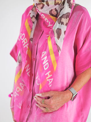 Eine Frau trägt das OFF#DLY Tuch 130x130 leo pink aus 100% Viskose, kombiniert mit einem rosa Shirt und goldenen Ringen, präsentiert modisch und elegant.