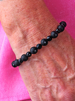 Glam & Rock Armband Edelstein Onyx, ein schwarzes, matt glänzendes Onyx-Kugelkette-Armband, getragen am Handgelenk, mit Perlen von 5 und 8 mm Durchmesser, aus Onyx und Edelstahl.