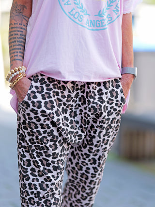 Person trägt die OFF#DLY Leo Short rosa, eine lässige Leo-Hose mit elastischem Bund und Kordelzug. Sichtbar sind seitliche Eingrifftaschen und das markante Animal-Print-Design.