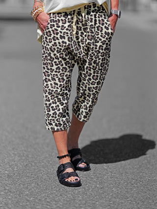 Person trägt OFF#DLY Leo Short gelb mit auffälligem Leopardenmuster. Hose hat elastischen Bund mit Kordelzug und seitliche Taschen, perfekte Kombination aus Stil und Komfort.