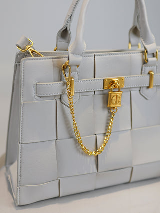 Enrico Coveri Flechttasche grau aus Kunstleder mit elegantem Flechtmuster, goldenen Details inklusive Kette mit Schloss und Schnallen, zwei Tragehenkeln, abnehmbarem Schulterriemen und Reißverschlussfächern.