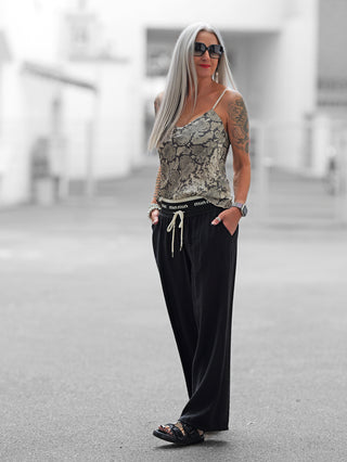 Das OFF#DLY Top Levorno taupe/grey zeigt einen ausdrucksstarken Snake-Print mit verstellbaren Trägern und lockerem Schnitt, ideal für vielseitige Kombinationen. Material: 100% Viskose.