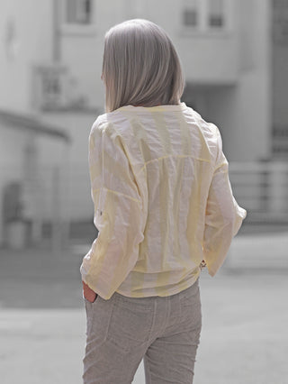 Die OFF#DLY Stripe Bluse Taggia butteryellow zeigt ein gelb-weißes Streifenmuster, lässig geschnitten mit aufrollbaren Ärmeln und Knopfleiste, perfekt für sommerliche Outfits.