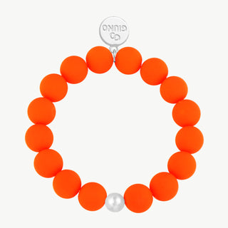OFF#DLY Armband orange: Ein elastisches Armband mit etwa achtzehn matten, neon-orangenen Perlen und einer silbernen Perle. Ein rundes Metall-Tag mit „GIUNO“ befindet sich oben.