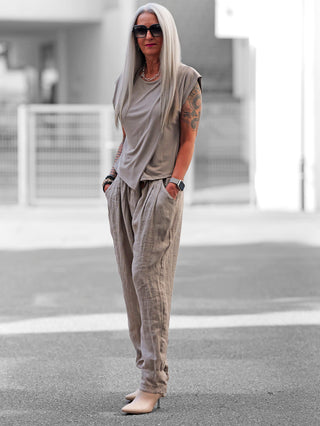 Nahaufnahme eines OFF#DLY Tee Neapel taupe mit raffiniertem Faltendesign, das eine elegante Note verleiht, getragen von einer Person in lässiger Straßenmode, passend für stilvolle Alltagslooks.