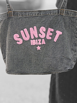 OFF#DLY Bag Sunset Ibiza black denim: Schwarze Denim-Tasche mit pinkem Schriftzug SUNSET und IBIZA darunter; pinker Stern. Größe 40x30x15 cm, 100% Baumwolle, zwei Henkel.
