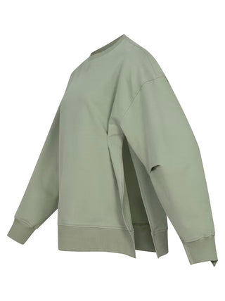 Nahaufnahme des Gitta Banko Sweater DORO matcha mit detailliertem Blick auf den Ärmel und den Stoff, der einen modernen, leicht kastigen Schnitt und seitliche Schlitze zeigt.