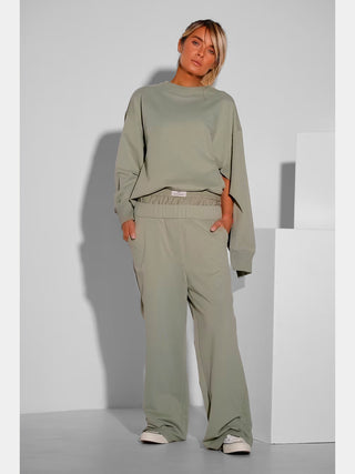 Nahaufnahme von Gitta Banko Sweater DORO matcha, das moderne Design mit seitlichen Schlitzen und kastigem Schnitt zeigt. Perfekte Mischung aus Komfort und Stil, ideal für modebewusste Frauen.