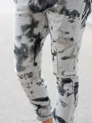 Die OFF#DLY Denim Castiglione grey/black zeigt moderne Batik-Optik mit schwarzen Flecken auf den Beinen, kombiniert Lässigkeit und Stil mit Destroyed-Details und schmal zulaufendem Schnitt.