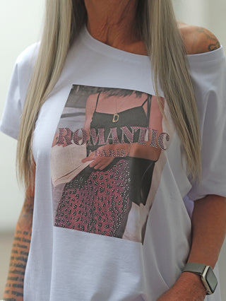 OFF#DLY Tee Romantic white: Oversized weißes T-Shirt mit stilisiertem Print einer Frau im schwarzen Top und pinkem Rock, überlagert von ROMANTIC und PARIS. Perfekt für einen femininen, glamourösen Look.
