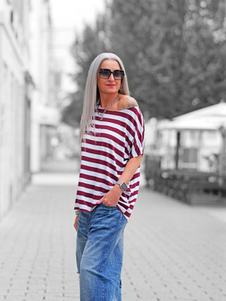 Person trägt das OFF#DLY Marion Stripe Tee white/bordeaux, ein locker geschnittenes, gestreiftes Kurzarmshirt mit Rundhalsausschnitt, passend zu Jeans und Accessoires, für einen stilvollen, lässigen Look.