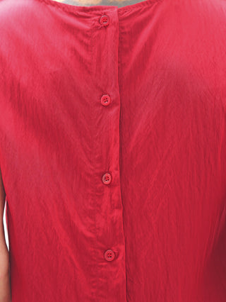Nahaufnahme des OFF#DLY Top Follonica red mit durchgehender roter Knopfleiste. Das ärmellose Design und die vertikale Knopfleiste verleihen dem Kleidungsstück einen modernen, stilvollen Look.
