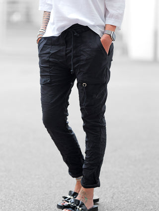 OFF#DLY Pant Iseo black: Schwarze Joggerhose mit Crinkle-Optik, Kordelzug, Cargo-Details und D-Ring. Kombiniert mit Ruffle-Sandalen und Accessoires für lässigen Streetstyle.