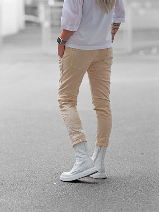 OFF#DLY Joggpant Vellano beige: Slim-fit, sandbeige Hose mit elastischen Bündchen, modernen Cargotaschen und seitlichen Eingrifftaschen, getragen mit weißen High-Top-Sneakers. Perfekt für sportlich-lässigen Sommerlook.