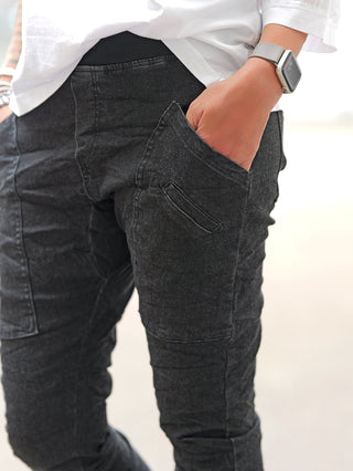 Nahaufnahme der OFF#DLY Joggpant Vellano black denim, getragen mit weißem Oberteil. Die Hose hat eine schlanke Passform und einen urbanen Look mit Komfort eines Joggers.
