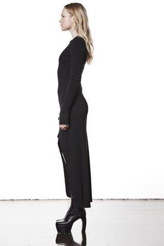 Thom Krom Dress WD 52 black: Schlanke Silhouette in bodenlangem, figurbetontem Design mit asymmetrischem Saum und langen Ärmeln, kombiniert mit groben schwarzen Plattformstiefeln.