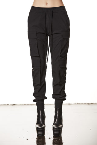 Thom Krom Pant WP 15 black: Schwarze, eng anliegende Cargo-Jogginghose mit elastischem Bund, mehreren Beintaschen und breiten Bündchen, kombiniert mit schwarzen Leder-Plattformstiefeletten.
