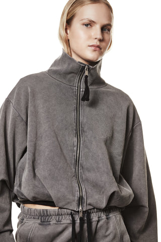 Thom Krom Jacket WSJ 494 used grey: Person trägt graue Jacke mit hohem Kragen, schwarzen Zugbändern und Reißverschluss, kombiniert mit grauer Hose. Jacke zeigt weite Ärmel und elastischen Saum.