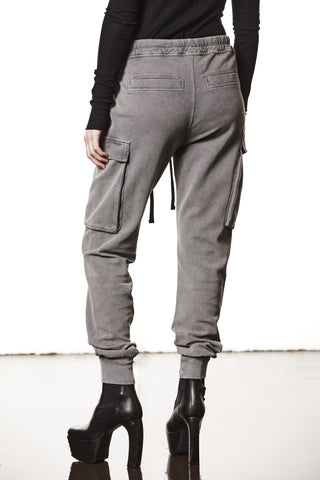Thom Krom Pant WST 417 used grey: Cargo-Joggerhose mit Oberschenkeltaschen und rückseitigen Taschen, kombiniert mit schwarzen Plateau-Stiefeletten mit klobigem Absatz, präsentiert in einem Studio-Setting.