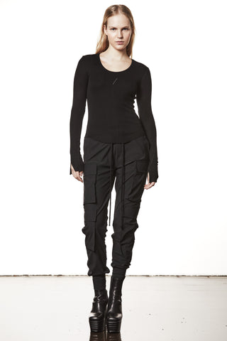 Junge Frau trägt das Thom Krom Sweater WTS 585 black mit langen Ärmeln, Daumenlöchern und körperbetontem Schnitt, kombiniert mit schwarzen Cargohosen und Plattform-Stiefeln.