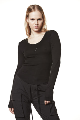 Junge Frau trägt das Thom Krom Sweater WTS 585 black mit tiefem Rundhalsausschnitt, figurbetonter Passform und verlängerten Ärmeln mit Daumenlöchern, kombiniert mit lockeren Cargohosen.