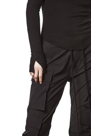 Thom Krom Sweater WTS 585 black mit langen Ärmeln und Daumenöffnungen, kombiniert mit schwarzen Cargo-Hosen mit Taschen und Kordelzug.