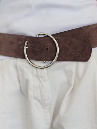 Nahaufnahme des BSB Belt brown one Size: Ein breiter brauner Wildledergürtel mit runder silberner Metallschnalle, getragen um die Taille über einer hellen Hose und einem weißen Oberteil.