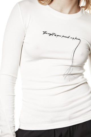 Thom Krom Sweat WTS583 cream: Figurbetontes, weißes Langarmshirt mit schwarzer Script-Stickerei The night is your friend, my love auf der Brust und hängenden Fäden, kombiniert mit dunkler Hose.
