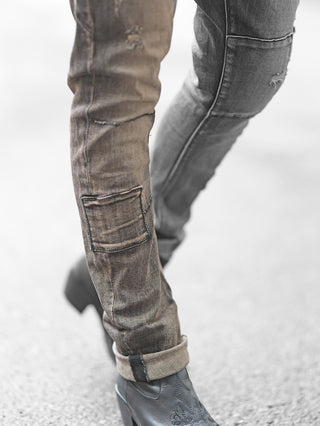 Nahaufnahme von Beinen in OFF#DLY Denim Cecina black Denim Jeans mit leicht zerstörten Details, aufgesetzter Tasche und umgeschlagenen Säumen, kombiniert mit schwarzen Stiefeletten.