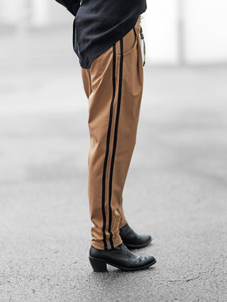 OFF#DLY Pamt Turin camel: Tan Jogger-Hose mit schwarzen Streifen, elastischer Bund, schwarze Stiefel, sportlich-schicke Optik, ideal für City- und Reise-Stil.