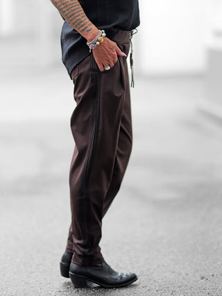 OFF#DLY Pamt Turin brown Hose zeigt sich sportlich und chic mit leicht konischem Bein, schwarzen Galonstreifen und elastischem Bund. Kombiniert mit schwarzen Lederstiefeln und Armbändern am Handgelenk.
